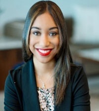 a smiling woman in a black blazer and leopard print shirt